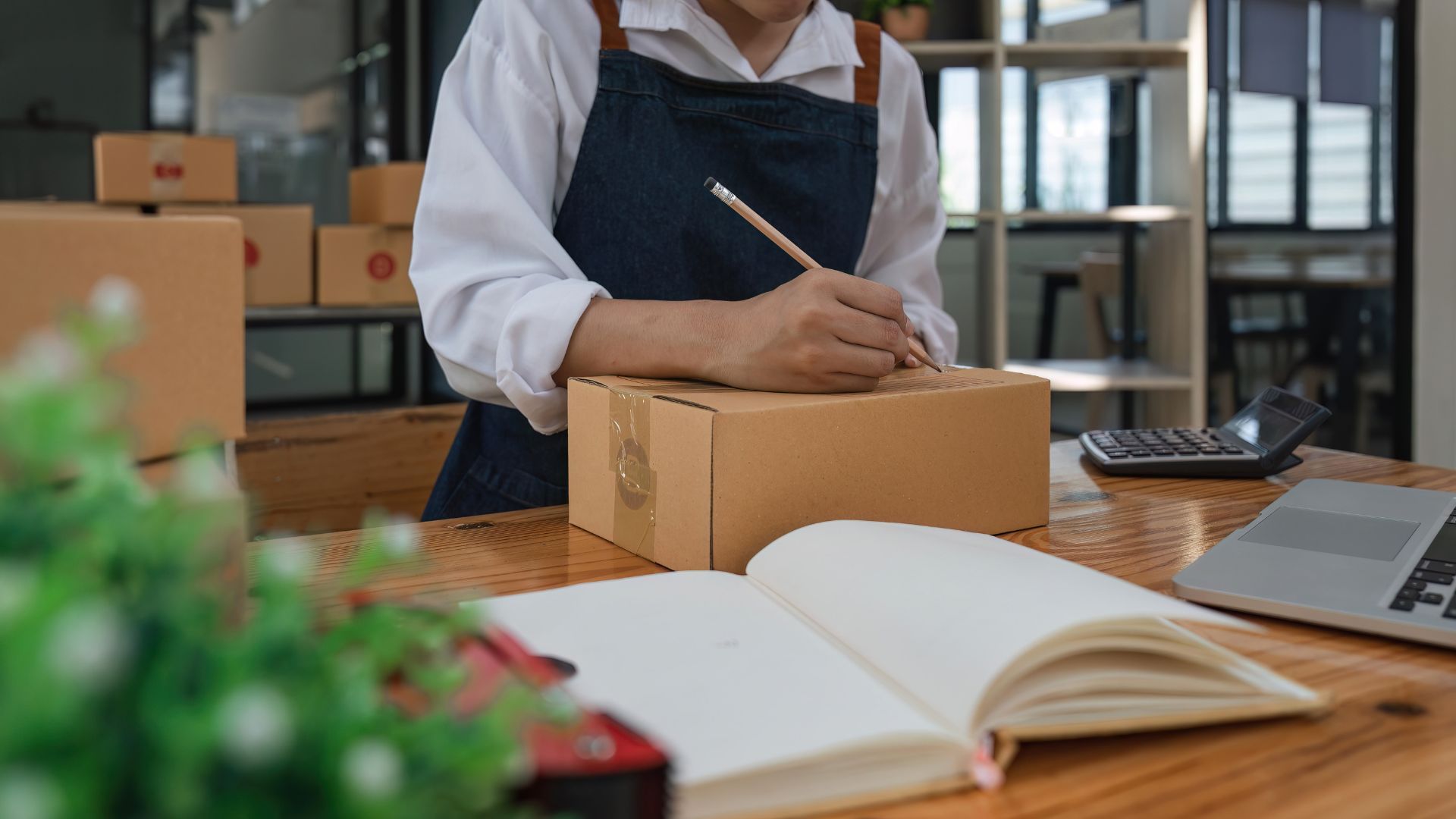 A business owner preparing a package for delivery, representing Ink Arrow Marketing Co. and its expertise in blending digital marketing and traditional marketing strategies.