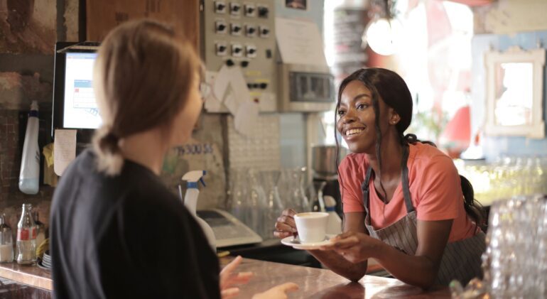 An employee serving a client coffee, highlighting a local business and Ink & Arrow’s commitment to local helping local initiatives and community support.