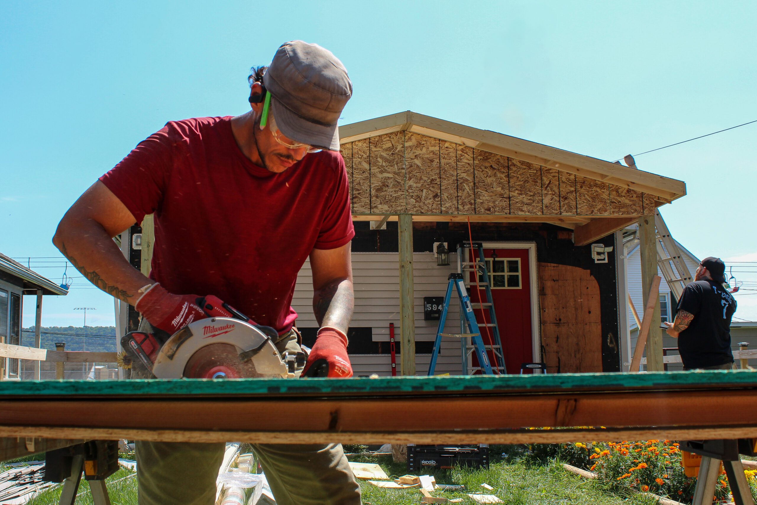 MDi construction worker cutting wood to frame a residential porch roof during new home construction