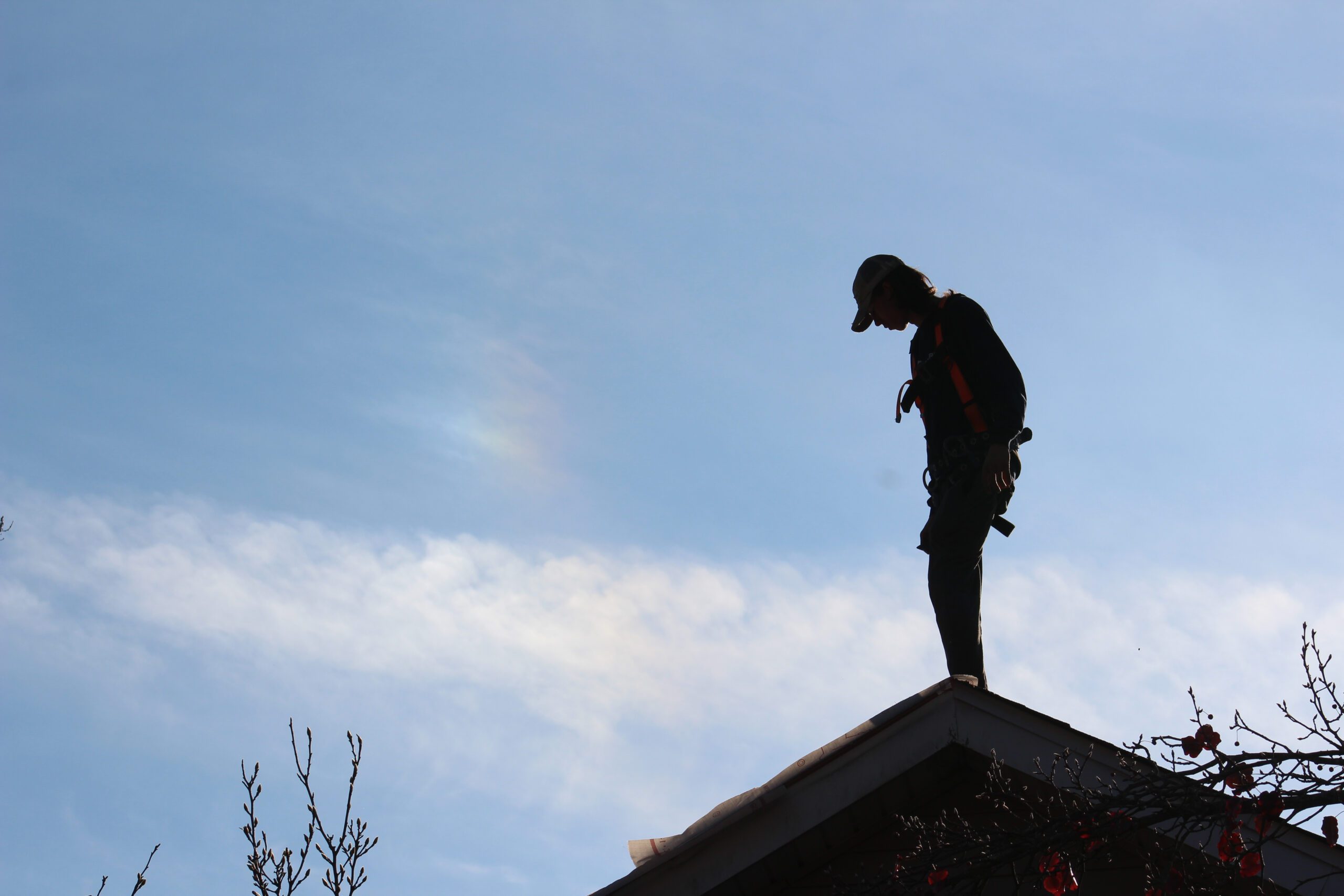 Roofer on top of a residential roof replacing asphalt shingles during a professional roofing service