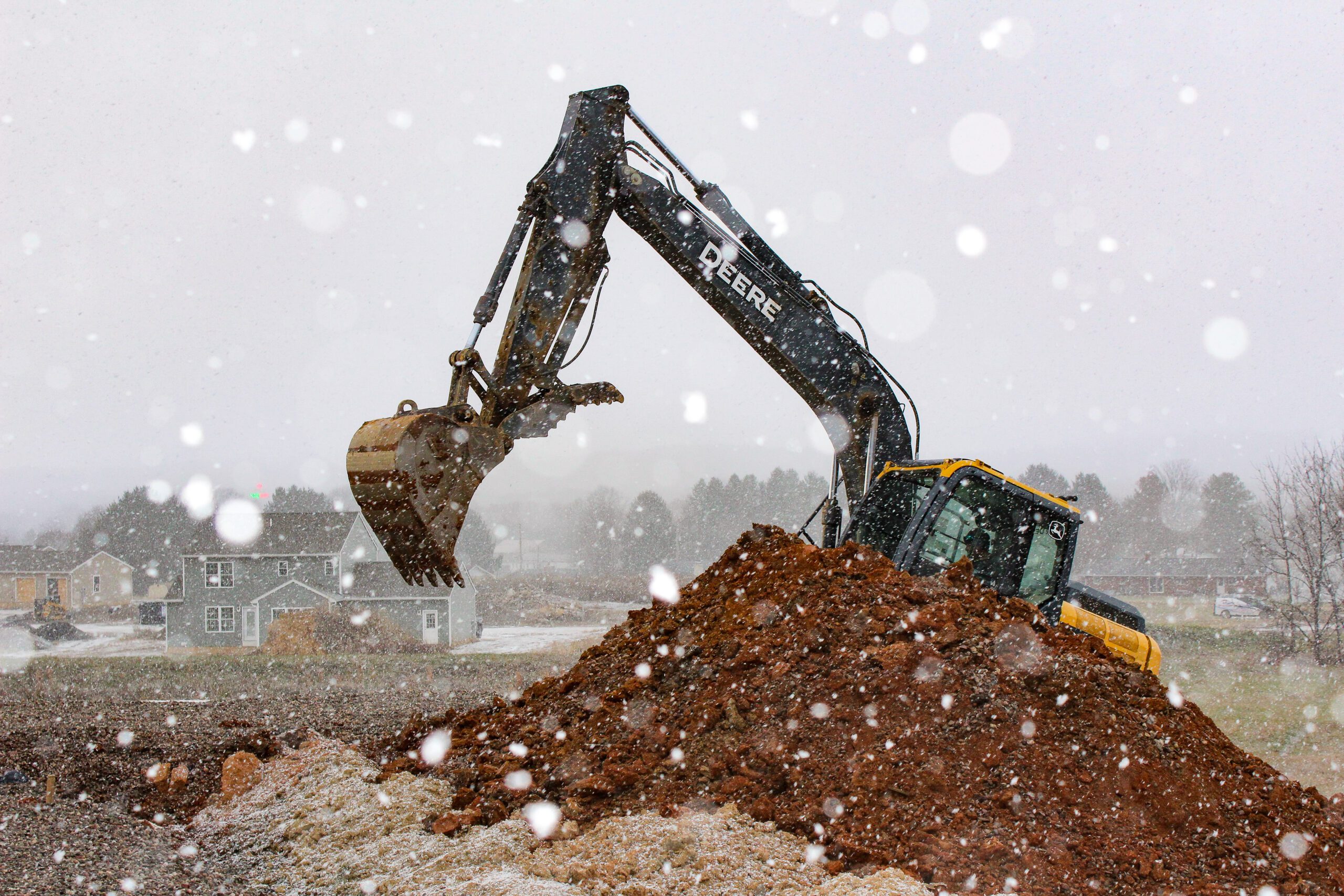 Backhoe digging foundation for new residential home construction on a cleared lot