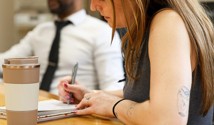 Director of Marketing taking notes during a morning strategy meeting with cross-functional team