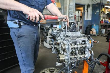 Mechanic assembling motor using a torque wrench for precise tightening during engine repair
