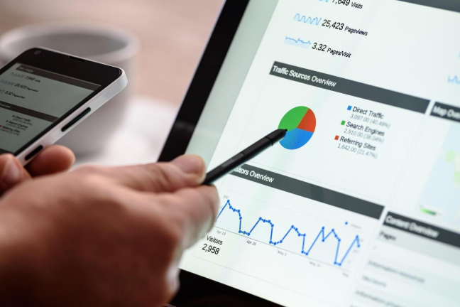 Ink Arrow employee hand holding a pen and using a tablet to point out business statistics for a Google Business Profile with clear data insights.